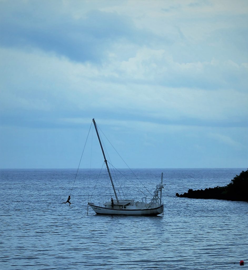 boy swinging off boat in Roatan