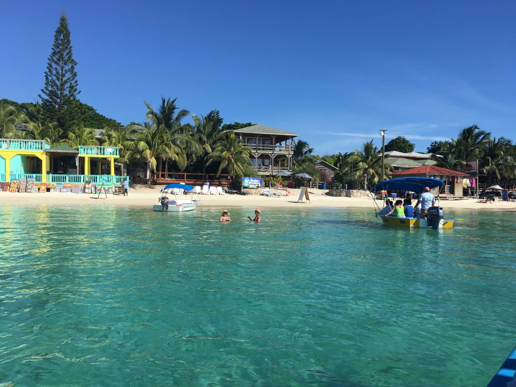 Beach with boats and swimmers in Roatan