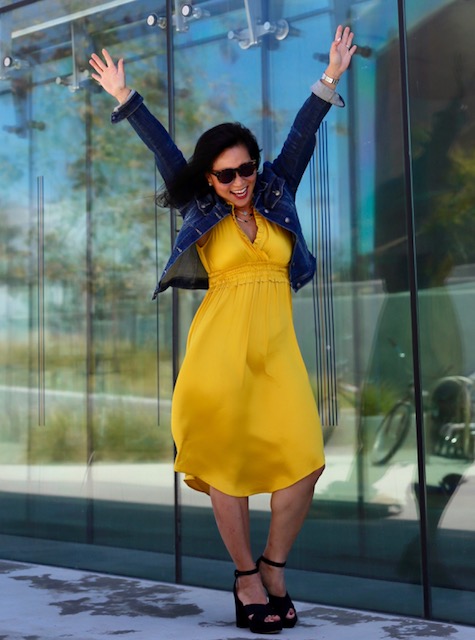 Woman in yellow dress reaching skyward