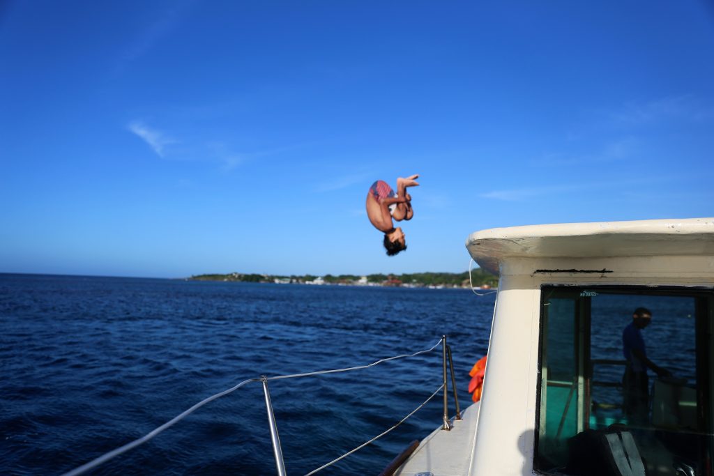 boy jumping off a boat into the ocean