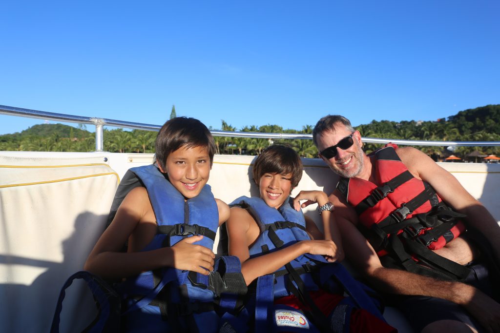 two boys and a man in life jackets on a boat